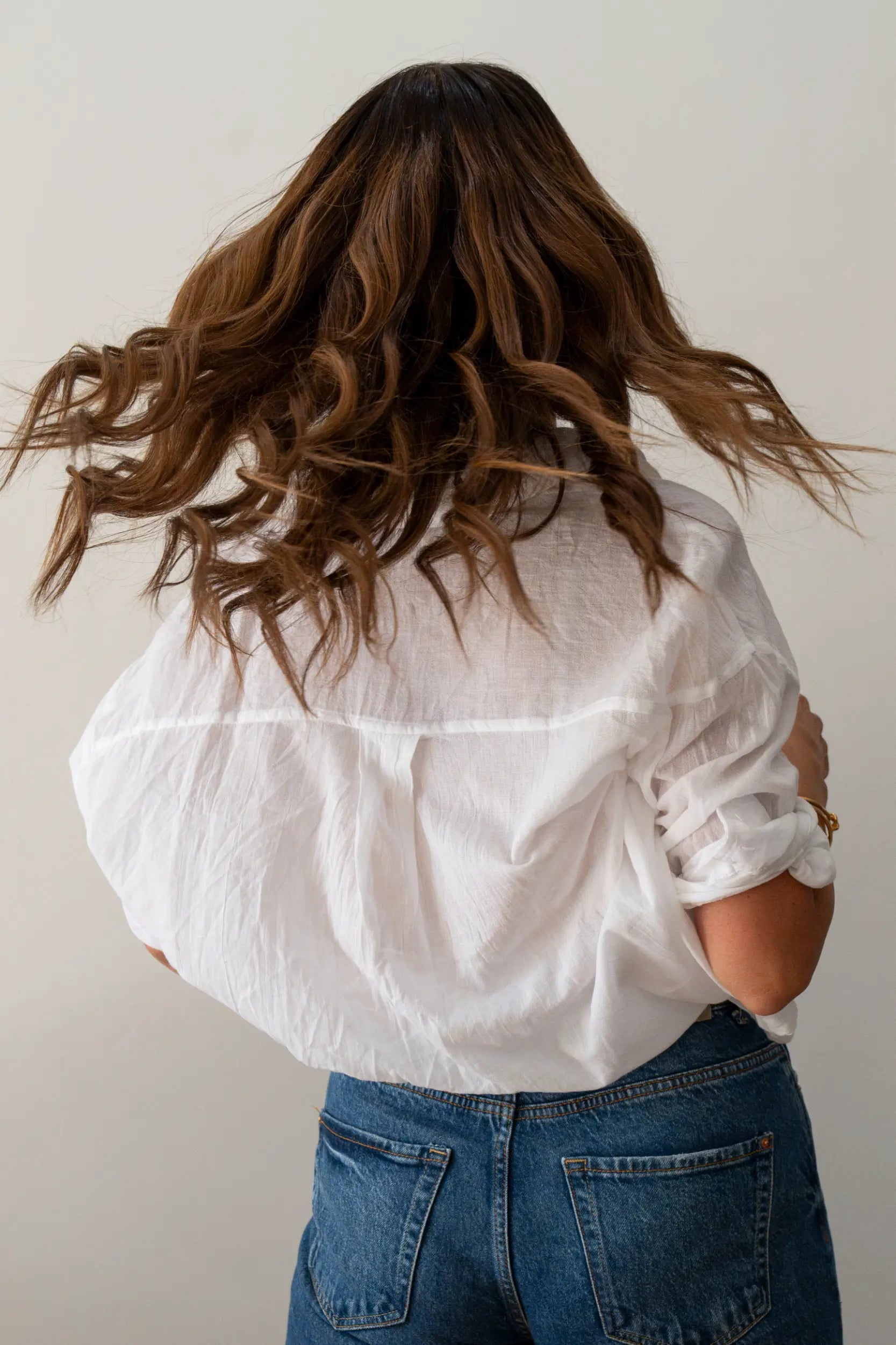 Back view of a woman flicking long wavy brunette human hair