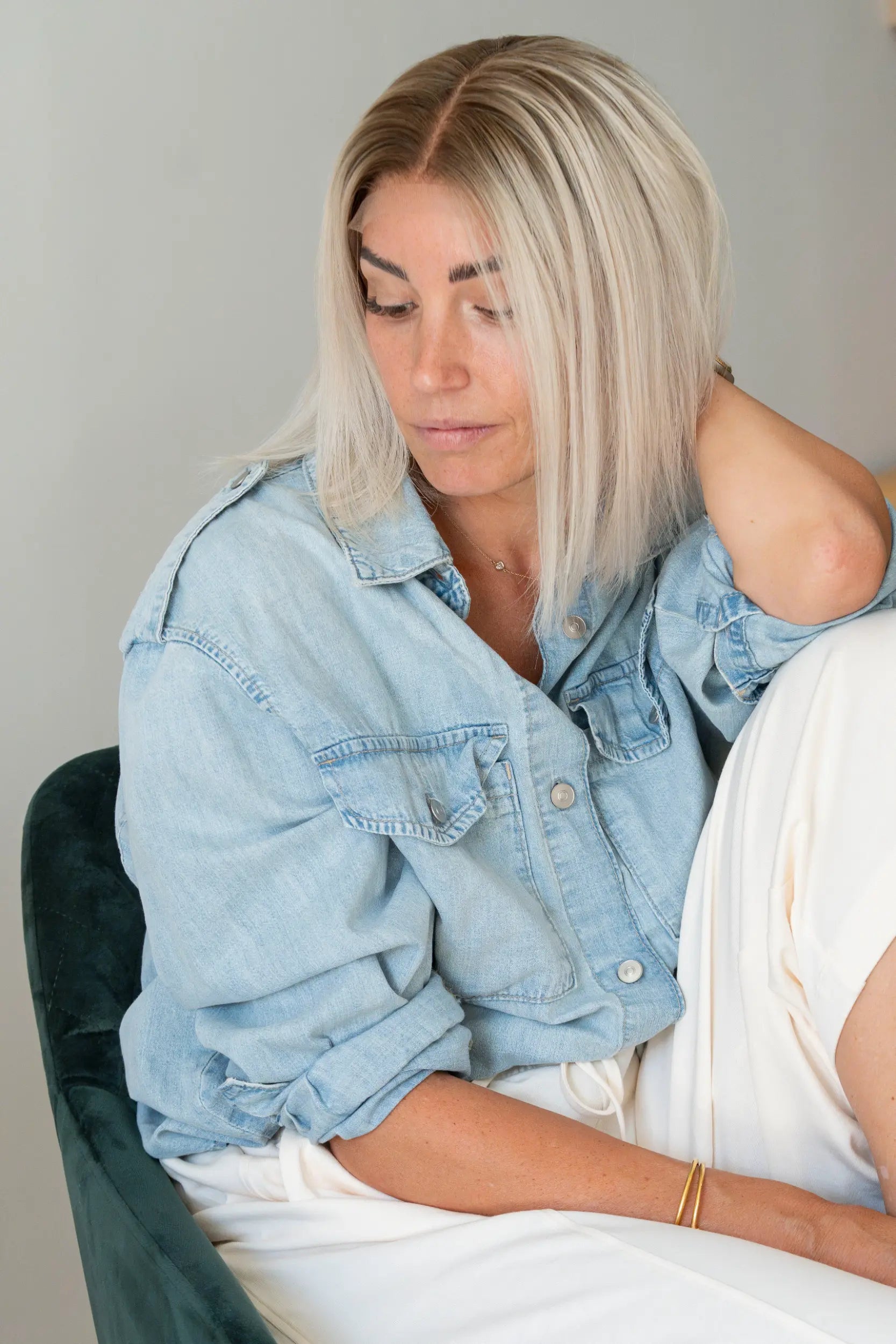 Woman in a denim jacket wearing a Vanilla Sand rooted blonde lob wig