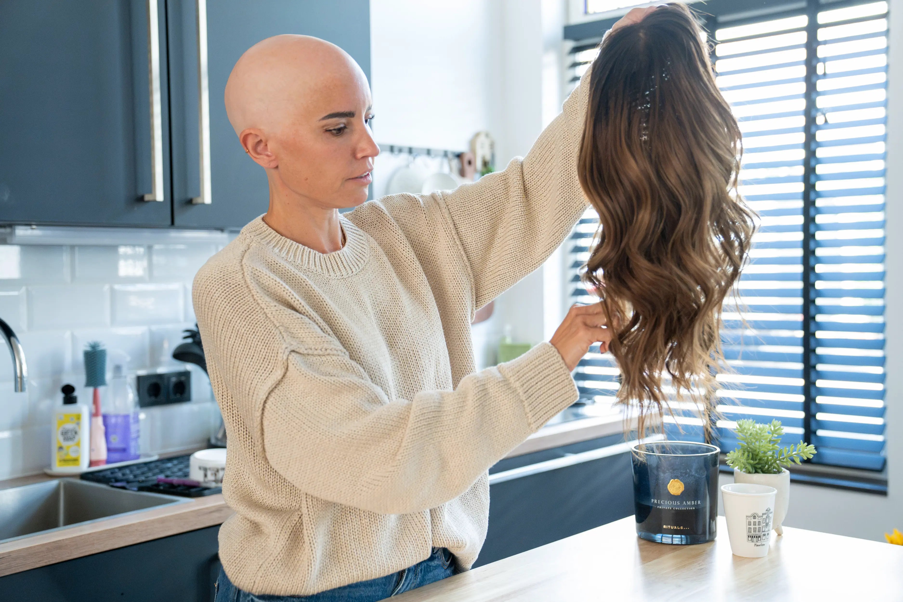Natalie holding up a long wavy human hair wig to show the lace hairline